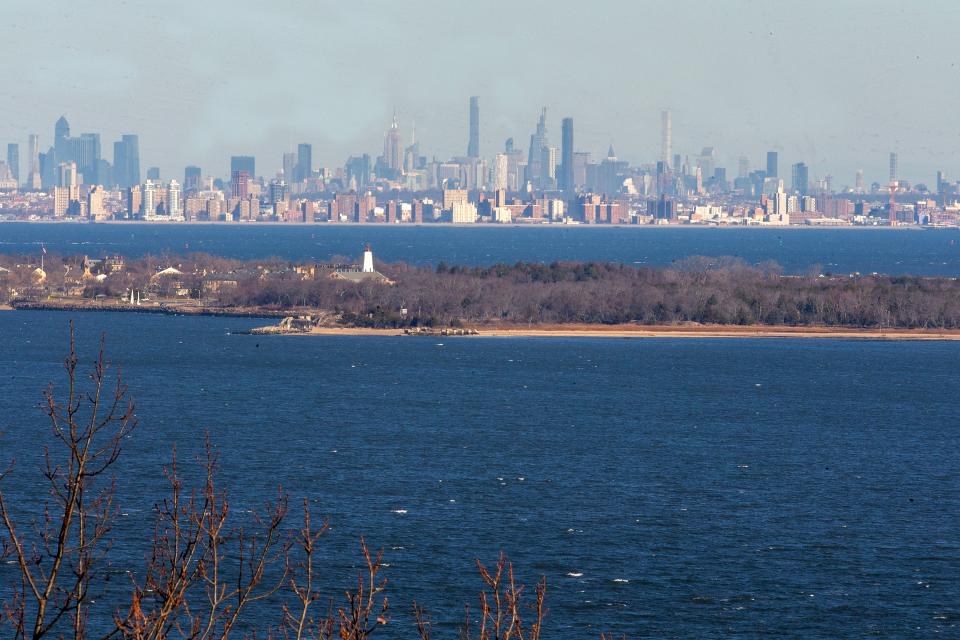 The Sandy Hook landscape between the Sandy Hook Lighthouse and The Marine Academy of Science and Technology (MAST), which is believed to be where Refugeetown — an encampment of escaped slaves that fought with the British during the American Revolution — was located, photographed from the Mount Mitchill Scenic Overlook in Atlantic Highlands, NJ, with the New York City skyline in the distance, Tuesday, December 20, 2022.