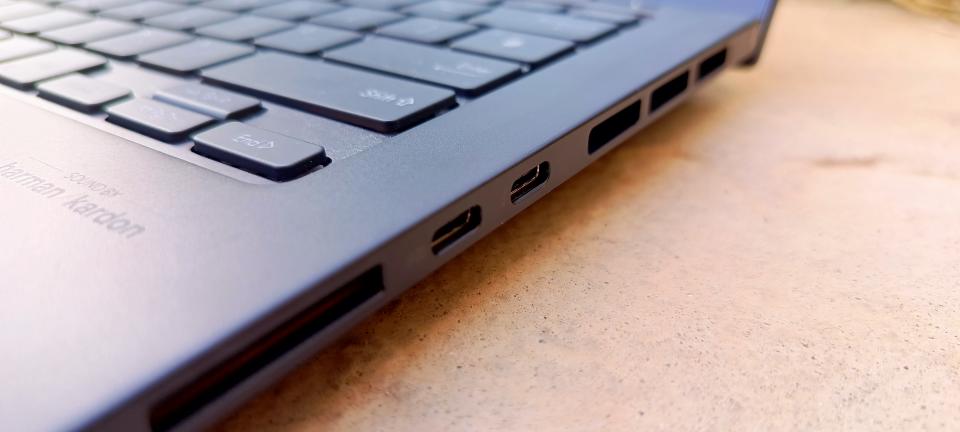 A black ASUS Zenbook Pro 14 OLED sitting on a patio in front of a grassy lawn