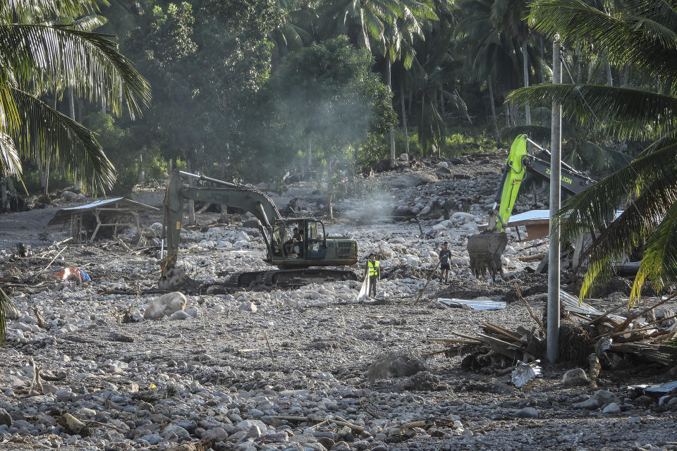 Rescuers use a backhoe to search for missing bodies in a mudslide after Tropical Storm Nalgae hit Barangay Kusiong, Datu Odin Sinsuat, Maguindanao province, southern Philippines on Monday Oct. 31, 2022. Philippine officials say more than 100 people have died in one of the most destructive storms to lash the Philippines this year. (AP Photo)