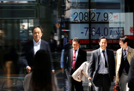 FILE PHOTO: People walk past an electronic board showing Japan's Nikkei average outside a brokerage in Tokyo, Japan, March 23, 2018. REUTERS/Toru Hanai