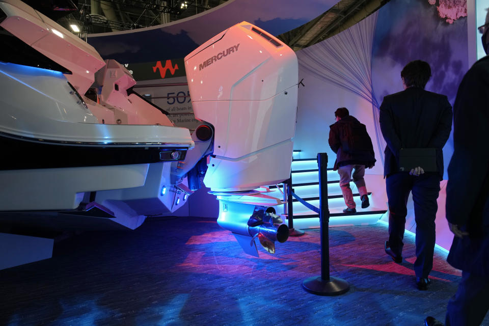 People walk by a Mercury V12 600 HP gas boat motor at the Brunswick booth during the CES tech show Friday, Jan. 6, 2023, in Las Vegas. (AP Photo/John Locher)