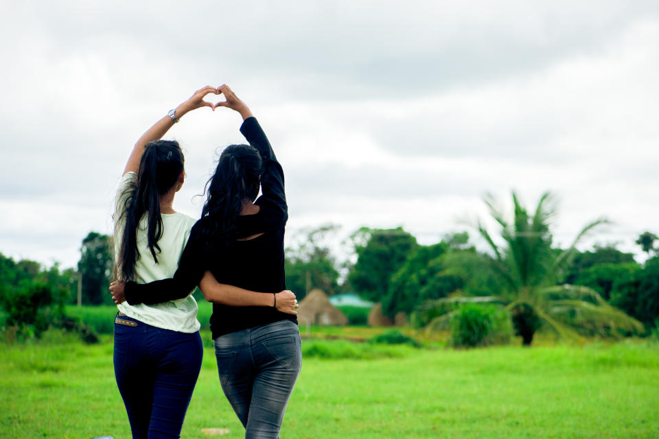 Two women making heart shape symbol with their hands, showing love and affection.