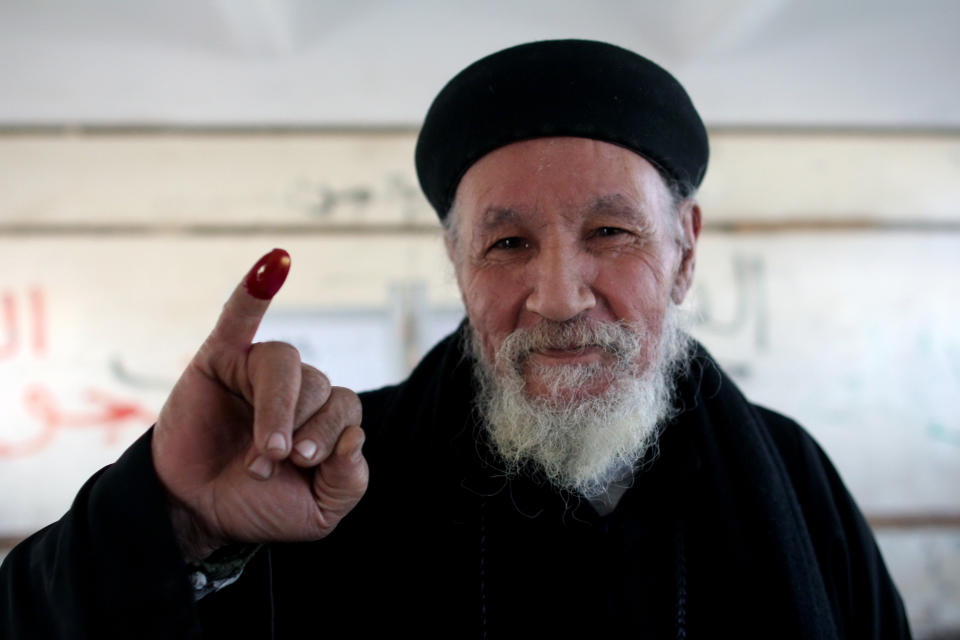 Father Antonious shows his inked finger after casting his ballot in a constitutional referendum inside a polling station in Dalga village of Minya, Egypt, Wednesday, Jan. 15, 2014. He is one of the priests of the Virgin Mary and St. Abraam Monastery that was looted and burned by supporters of ousted Islamist President Mohammed Morsi in August. Through violence or intimidation, Islamists in villages like this one used violence or intimidation to stop Christians from voting "no" to a 2012 constitution that had paved the way for the creation of an Islamic state. This time around, no one is stopping the Christians and they are voting "yes" on a new charter that criminalizes discrimination and instructs the next legislature to ease restrictions on building churches. (AP Photo/Roger Anis, El Shorouk Newspaper) EGYPT OUT