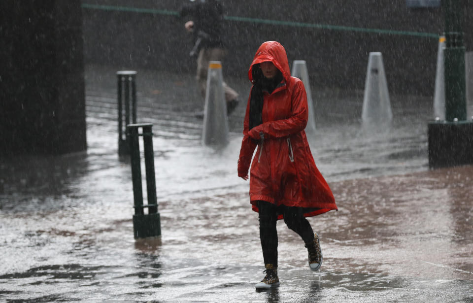 A woman in a red raincoat walks through Melbourne in heavy rain. AAP file picture