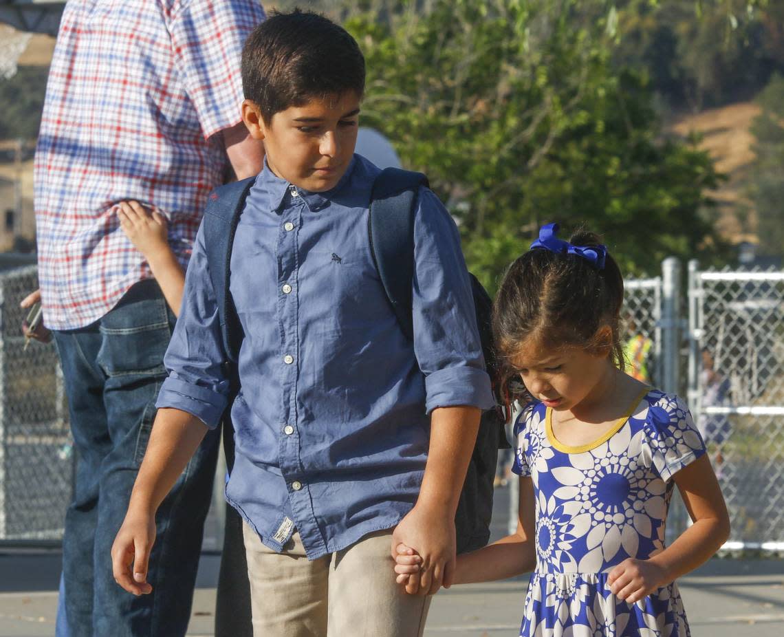 Benjamin Barakat, 10, walks his sister Audrey, 5, around the kindergarten area before school starts in 2018 at San Gabriel Elementary School in Atascadero.