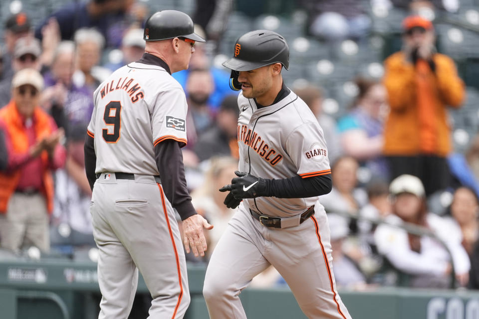 San Francisco Giants third base coach Matt Williams, left, congratulates Michael Conforto as he circles the bases after hitting a solo home run off Colorado Rockies starting pitcher Cal Quantrill in the fourth inning of a baseball game Thursday, May 9, 2024, in Denver. (AP Photo/David Zalubowski)