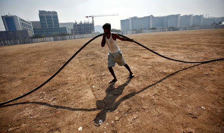 FILE PHOTO - A labourer pulls an underground cable at a construction site of a commercial complex in Mumbai January 20, 2011. REUTERS/Danish Siddiqui/File Photo