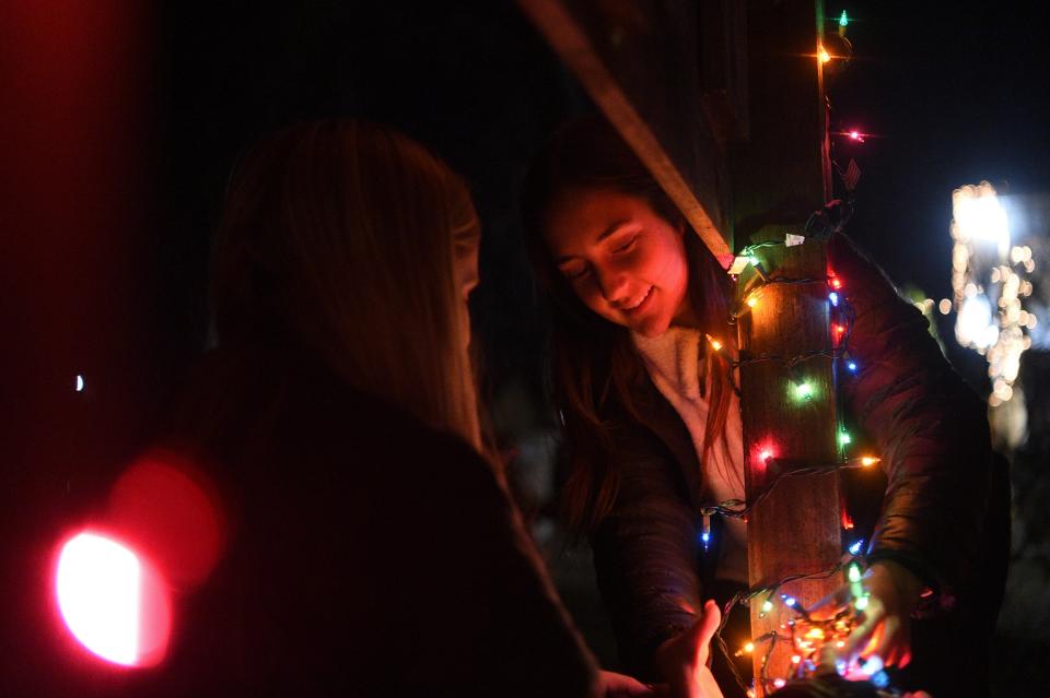 Molly Glenn and Sarah Benko decorate a sign at Light Up Lonsdale in Lonsdale, Wednesday, Nov. 29, 2023.