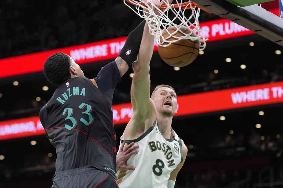 Boston Celtics' Kristaps Porzingis (8) dunks against Washington Wizards' Kyle Kuzma (33) during the first half of an NBA basketball game Friday, Feb. 9, 2024, in Boston. (AP Photo/Michael Dwyer)