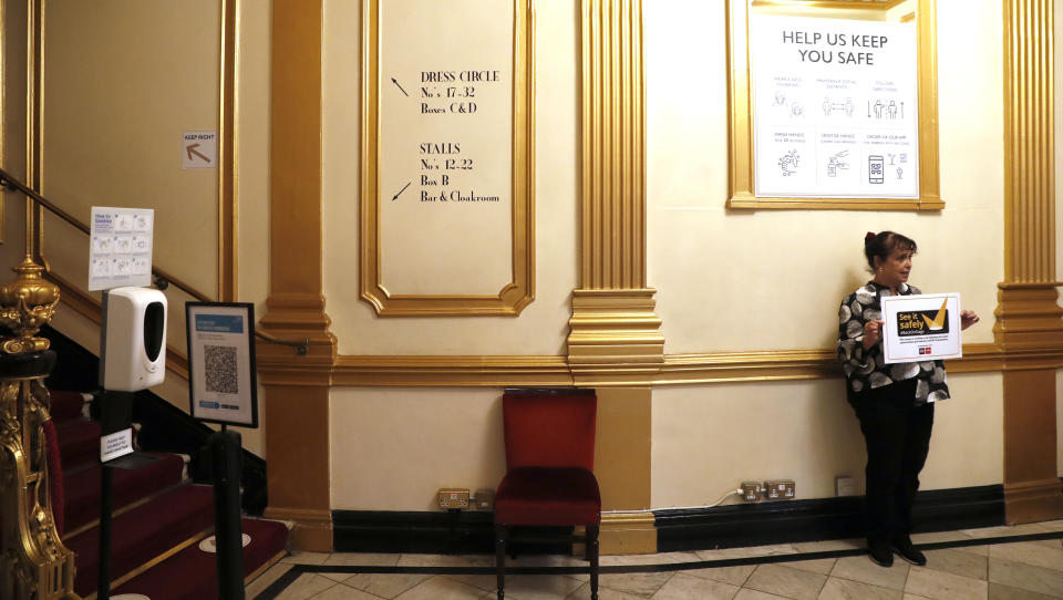 Nica Burns, theater owner and producer holds up a See it Safely sign as she speaks to the Associated Press in the foyer of the Apollo Theater where 'Everybody's Talking About Jamie' is making preparations to continue its run in London, Tuesday, April 20, 2021. The theaters in London's West End shut when lockdown began in March 2020, and have remained closed for most of the past 13 months. "We were the first to be closed," producer Nica Burns said. "And we were the last to come back." (AP Photo/Alastair Grant)