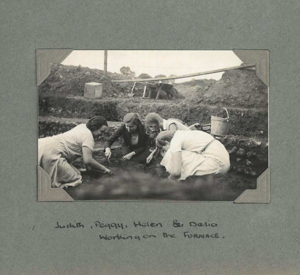 Four women in dresses excavate an Ancient Roman town