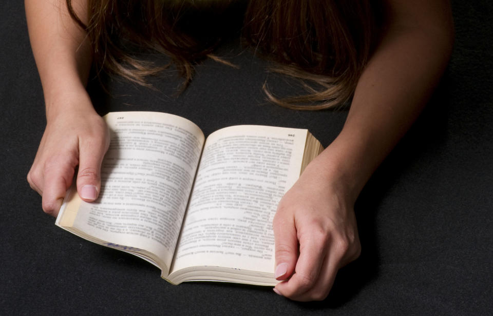 A girl reads from a book that sits in her lap