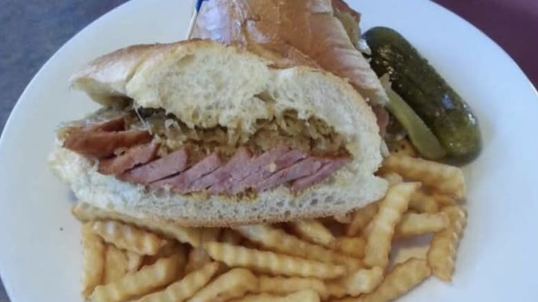 Sliced kielbasa in sandwich with pickle and fries