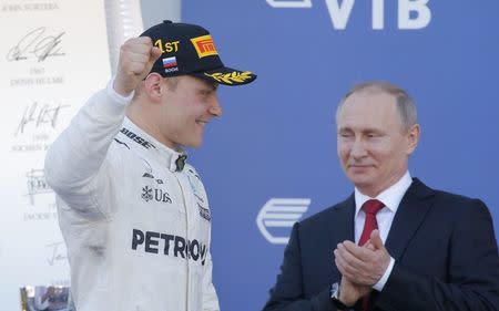 Formula One - F1 - Russian Grand Prix - Sochi, Russia - 30/04/17 - Mercedes Formula One driver Valtteri Bottas of Finland celebrates the victory on the podium, with Russian President Vladimir Putin seen in the background. REUTERS/Maxim Shemetov