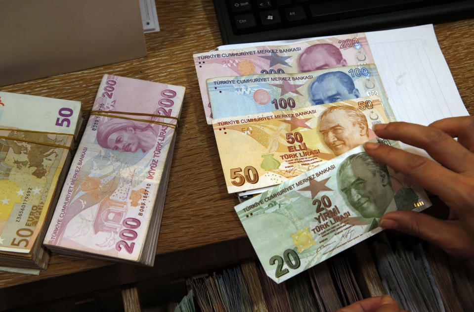 A worker at a currency exchange shop worker lays out Turkish lira banknotes depicting modern Turkey's founder Mustafa Kemal Ataturk, in Istanbul, Wednesday, Aug. 15, 2018. The Turkish lira has nosedived in value in the past week, but some Turks are reacting with defiance to their plunging currency and an escalating trade and political dispute with the United States, in an indication that they are ready to endure economic pain and risk further deterioration in a key yet troubled alliance dating from the Cold War. (AP Photo/Lefteris Pitarakis)