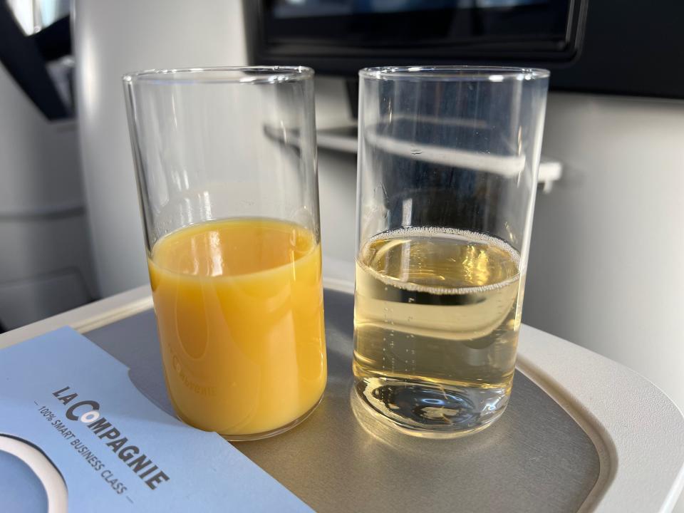 Flying on La Compagnie all-business class airline from Paris to New York — my orange juice and Champagne in two glasses before mixing.