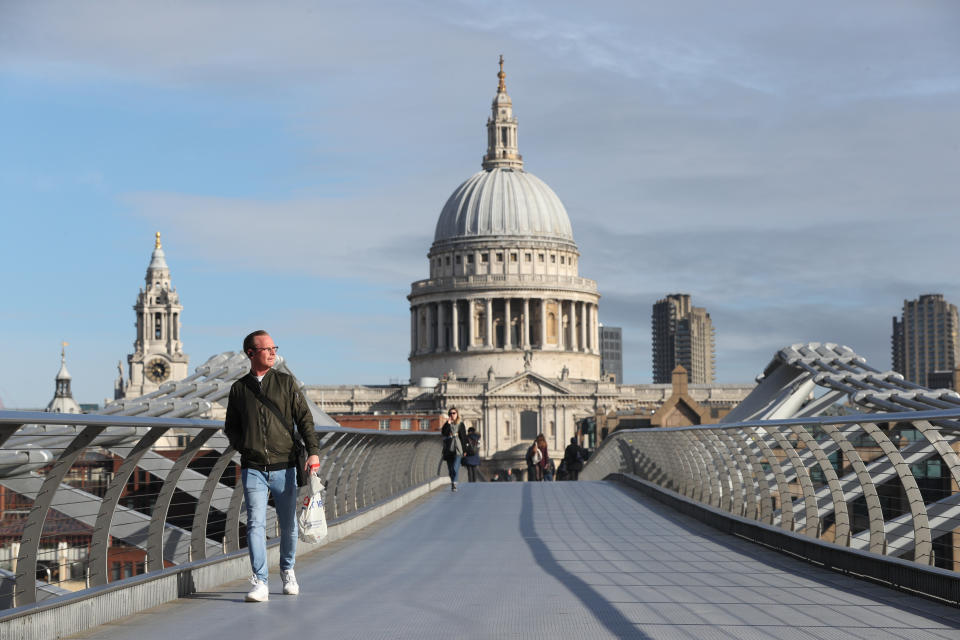 A commuter crosses a near-empty Millennium Bridge in London, the day after Prime Minister Boris Johnson called on people to stay away from pubs, clubs and theatres, work from home if possible and avoid all non-essential contacts and travel in order to reduce the impact of the coronavirus pandemic.