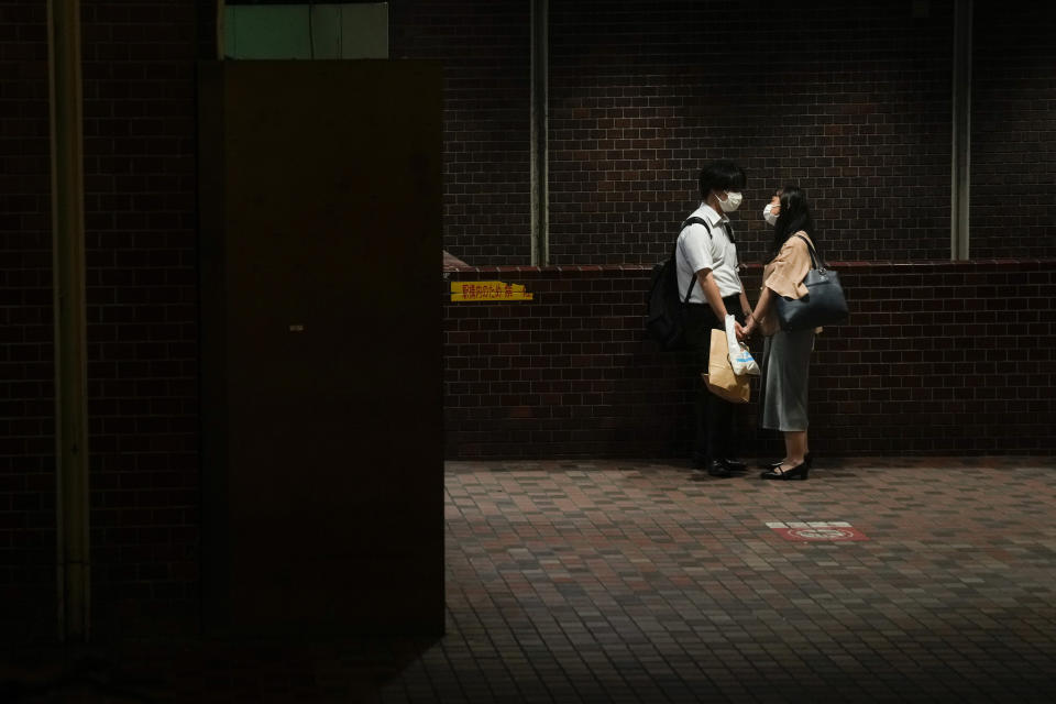 A couple hold hands at a subway station ahead of the 2020 Summer Olympics on Wednesday, July 14, 2021, in Tokyo. (AP Photo/Jae C. Hong)