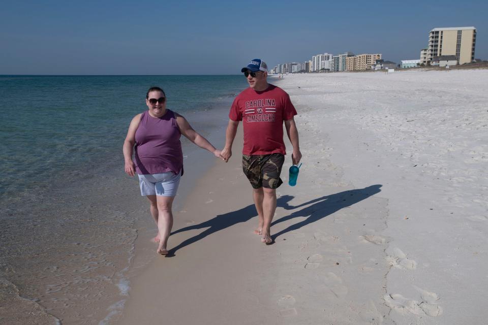 Chris and Allison Perske walk along the water's edge at Perdido Key's public beach access No. 4 on Friday, March 4, 2022. A judge shot down a group of condo owners' complaint that the beach access project on Perdido Key is illegal.