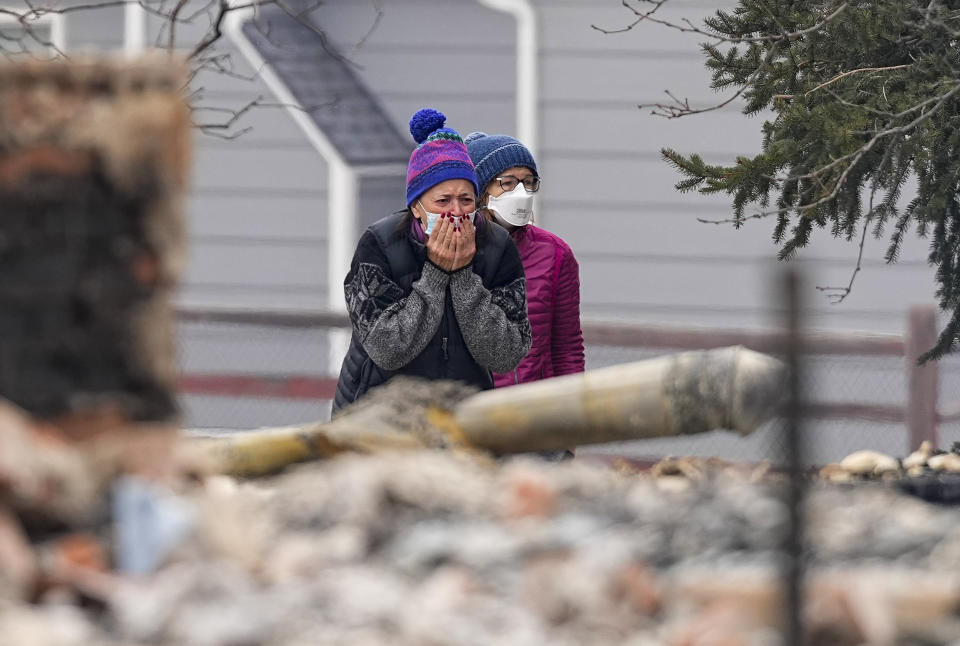 A woman cries as he sees the burned remains of a home destroyed by the Marshall Wildfire in Louisville, Colo., Friday, Dec. 31, 2021. Tens of thousands of Coloradans driven from their neighborhoods by a wind-whipped wildfire anxiously waited to learn what was left standing of their lives Friday as authorities reported more than 500 homes were feared destroyed. (AP Photo/Jack Dempsey)