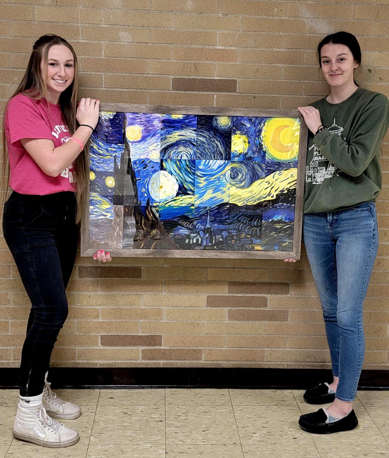 Jefferson High School art students Samantha Ledger, left, and Elizabeth Giles hold a framed mixed media artwork created by Sarah Carter’s 2-D design class. The project was inspired by Vincent van Gogh's famous oil painting "Starry Night."