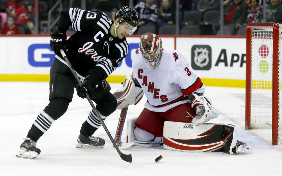 Carolina Hurricanes goalie Antti Raanta, right, stops New Jersey Devils center Nico Hischier (13) during the first period of an NHL hockey game Sunday, Jan. 1, 2023, in Newark, N.J. (AP Photo/John Munson)