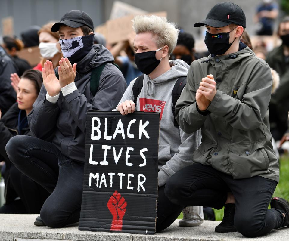 Protesters, some wearing PPE (personal protective equipment), including a face mask as a precautionary measure against COVID-19,  kneel as they hold placards during a demonstration in Manchester, northern England, on June 6, 2020, to show solidarity with the Black Lives Matter movement in the wake of the killing of George Floyd, an unarmed black man who died after a police officer knelt on his neck in Minneapolis. - The United States braced Friday for massive weekend protests against racism and police brutality, as outrage soared over the latest law enforcement abuses against demonstrators that were caught on camera. With protests over last week's police killing of George Floyd, an unarmed black man, surging into a second weekend, President Donald Trump sparked fresh controversy by saying it was a "great day" for Floyd. (Photo by Paul ELLIS / AFP) (Photo by PAUL ELLIS/AFP via Getty Images)