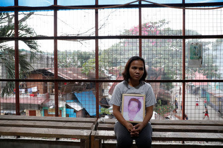 Kathrina Polo holds a picture of her late husband inside a church in Barangay Payatas district in Quezon City, Metro Manila in the Philippines December 11, 2017. REUTERS/Erik De Castro