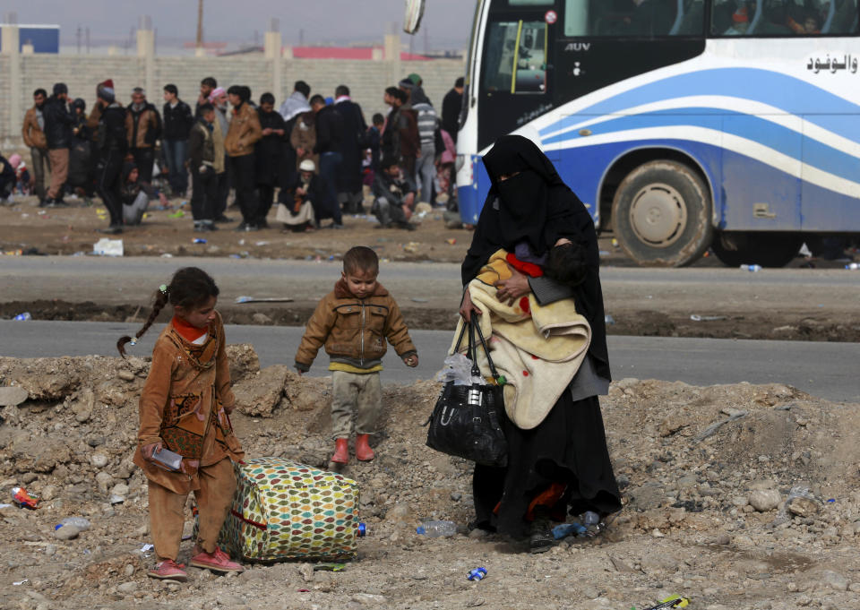 Displaced Iraqis, who fled fighting between Iraqi security forces and Islamic State militants, waiting at the gathering point to be taken for a camp for internally displaced people, in Bartella, around 19 miles (kilometers), from Mosul, Iraq, Saturday, Dec 31, 2016. (AP Photo/ Khalid Mohammed)