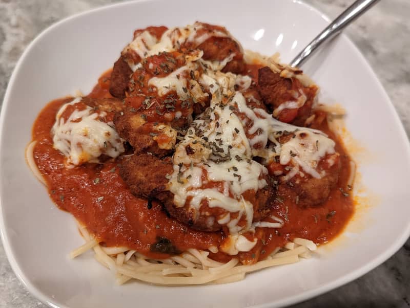 Spaghetti with chicken parmesan on top.