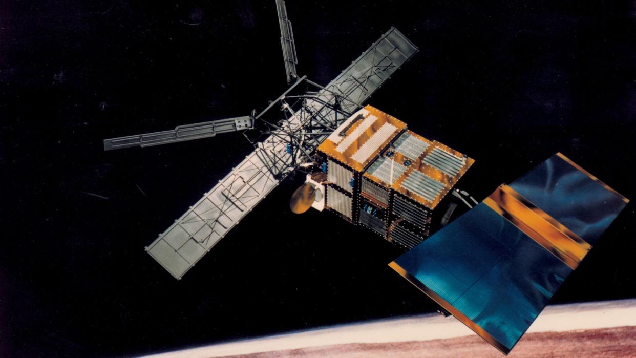  An illustration of a rectangular spacecraft with H-shaped solar sails in orbit above Earth. 