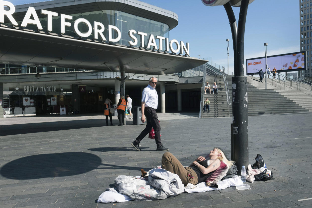 A homeless person lays in the sun outside Stratford Underground Station in London, Wednesday May 20, 2020. (Stefan Rousseau/PA via AP)