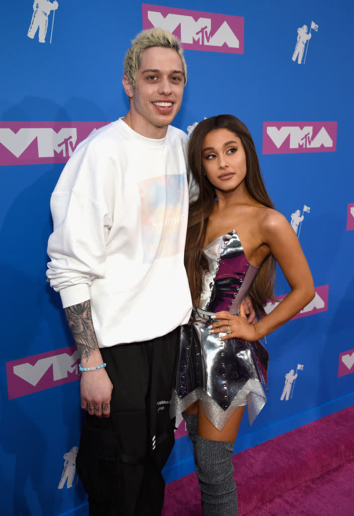 Pete Davidson in a casual sweatshirt and pants with Ariana Grande in a metallic mini-dress and thigh-high boots at the MTV event