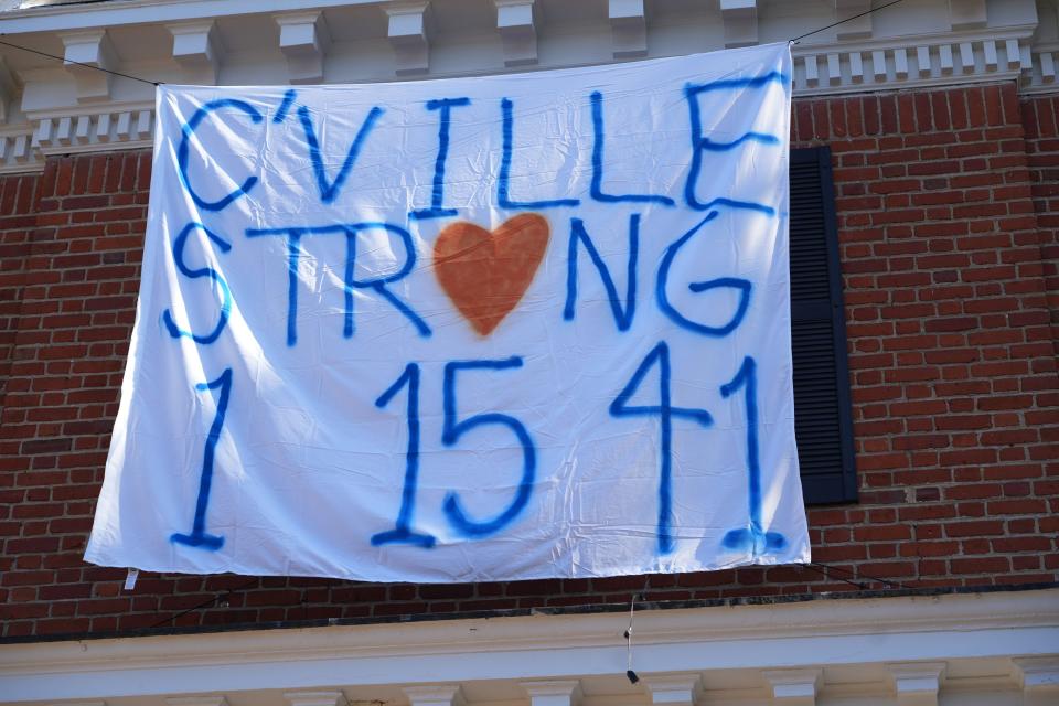 Members of Beta Theta Pi hang up a Charlottesville Strong poster after a shooting on Nov. 13, 2022, left three dead and two injured at the University of Virginia.