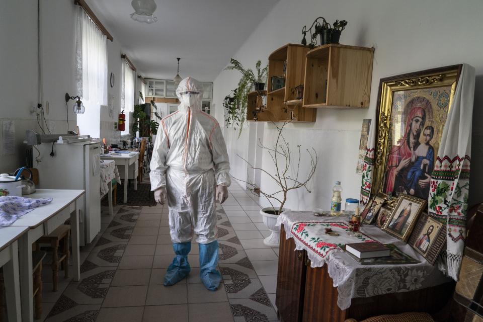 In this photo taken on Friday, May 1, 2020, a medical specialist wearing a special suit to protect against coronavirus, poses for photo next to an icon at a hospital in Pochaiv, Ukraine. Ukraine's troubled health care system has been overwhelmed by COVID-19, even though it has reported a relatively low number of cases. (AP Photo/Evgeniy Maloletka)