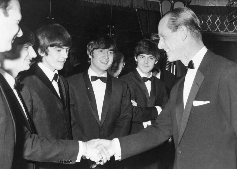 FILE - In this March 23, 1964 file photo, Britain's Prince Philip shakes hands with Ringo Starr as co-Beatles from left, George Harrison, John Lennon and Paul McCartney look on, at the Empire Ballroom in London, England. Buckingham Palace officials say Prince Philip, the husband of Queen Elizabeth II, has died, it was announced on Friday, April 9, 2021. He was 99. Philip spent a month in hospital earlier this year before being released on March 16 to return to Windsor Castle. Philip, also known as the Duke of Edinburgh, married Elizabeth in 1947 and was the longest-serving consort in British history. (AP Photo/File, Pool)
