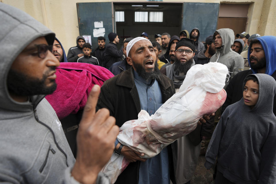 Palestinians chant Islamic slogans while carry the bodies of children killed in the Israeli strikes in the Gaza Strip in front of the morgue at Al Aqsa hospital in Deir al Balah, Gaza Strip, on Sunday, Feb. 18, 2024. (AP Photo/Adel Hana)