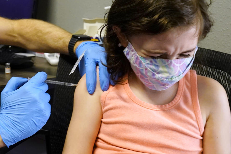 McKenna Brown, 10, turns her head away as she receives a Pfizer COVID-19 vaccine at Pucci's Pharmacy in Sacramento, Calif., Tuesday, Jan. 25, 2022. California is showing signs that it may have turned the corner on the latest omicron wave of the coronavirus pandemic, with cases falling and hospitalizations short of the overwhelming deluge that officials had predicted just weeks ago. (AP Photo/Rich Pedroncelli)