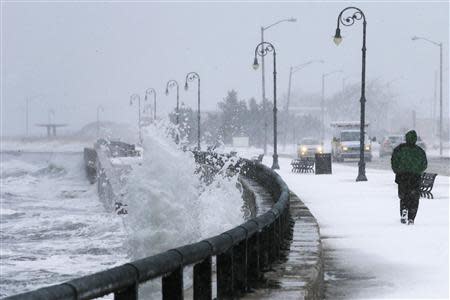 A man jogs past waves crashing against the seawall around high tide during a winter nor'easter snowstorm in Lynn, Massachusetts January 2, 2014. REUTERS/Brian Snyder