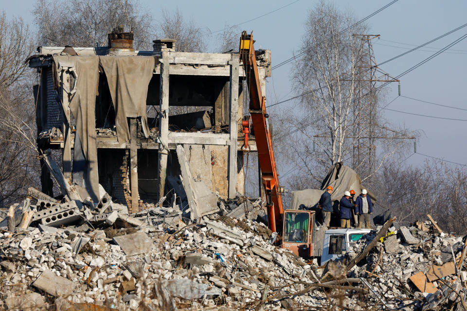 Workers remove debris of a destroyed building purported to be a vocational college used as temporary accommodation for Russian soldiers, 63 of whom were killed in a Ukrainian missile strike as stated the previous day by Russia's Defence Ministry, in the course of Russia-Ukraine conflict in Makiivka (Makeyevka), Russian-controlled Ukraine, January 3, 2023. REUTERS/Alexander Ermochenko