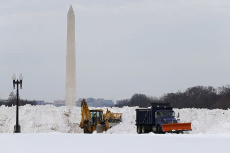 Workers use heavy machinery to pile snow removed from parking areas at the U.S. Capitol in Washington January 26, 2016. REUTERS/Jonathan Ernst