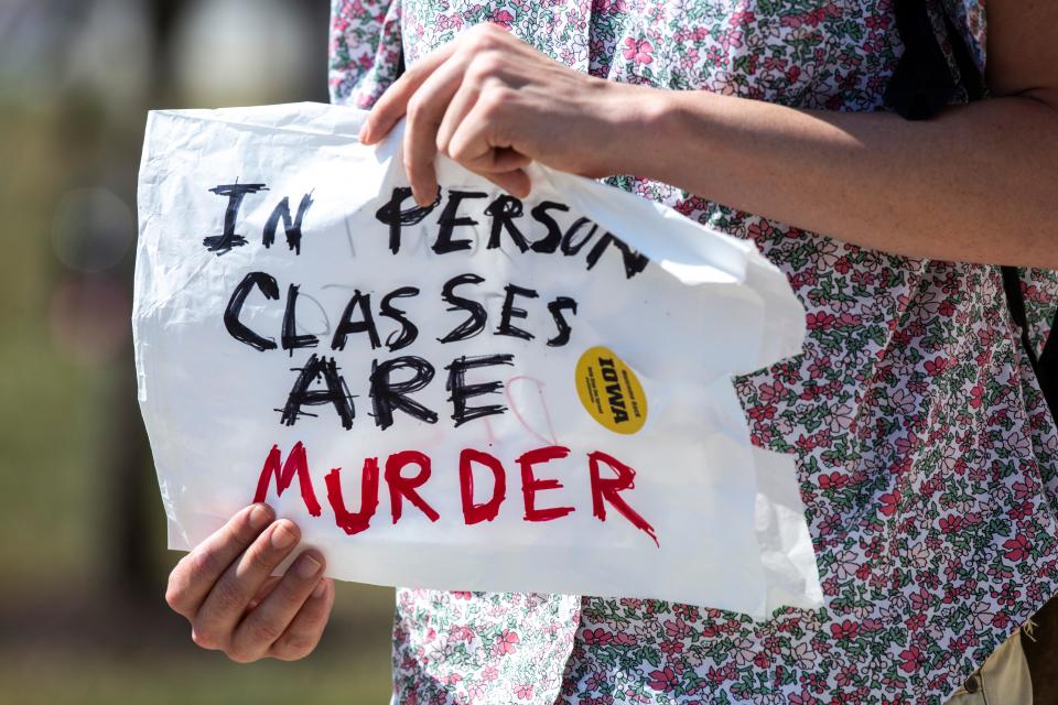 A person holds a sign, "In person classes are murder" during a recent protest against in-person classes on the University of Iowa campus. Many international students whose home countries are faring better in the pandemic are choosing to stay away from American colleges.