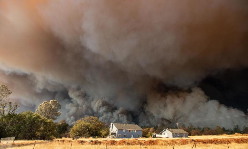 A home is overshadowed by towering smoke plumes in Paradise, California . Climate change-related risks will continue to grow without additional action, the report is set to warn.