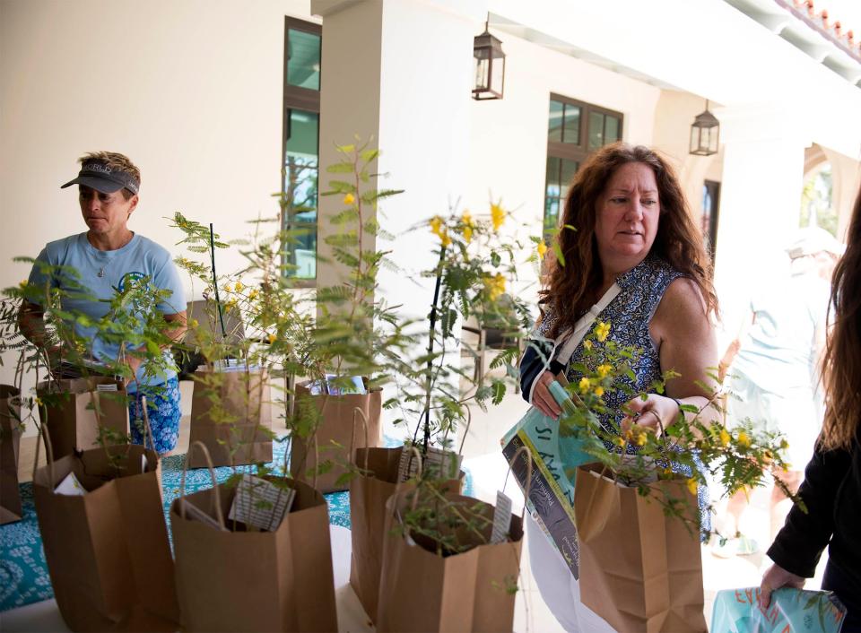 Diane Buhler, left, and Dawn Helton take home partridge pea plants provided by the Preservation Foundation of Palm Beach during the April 22 Earth Day celebration.