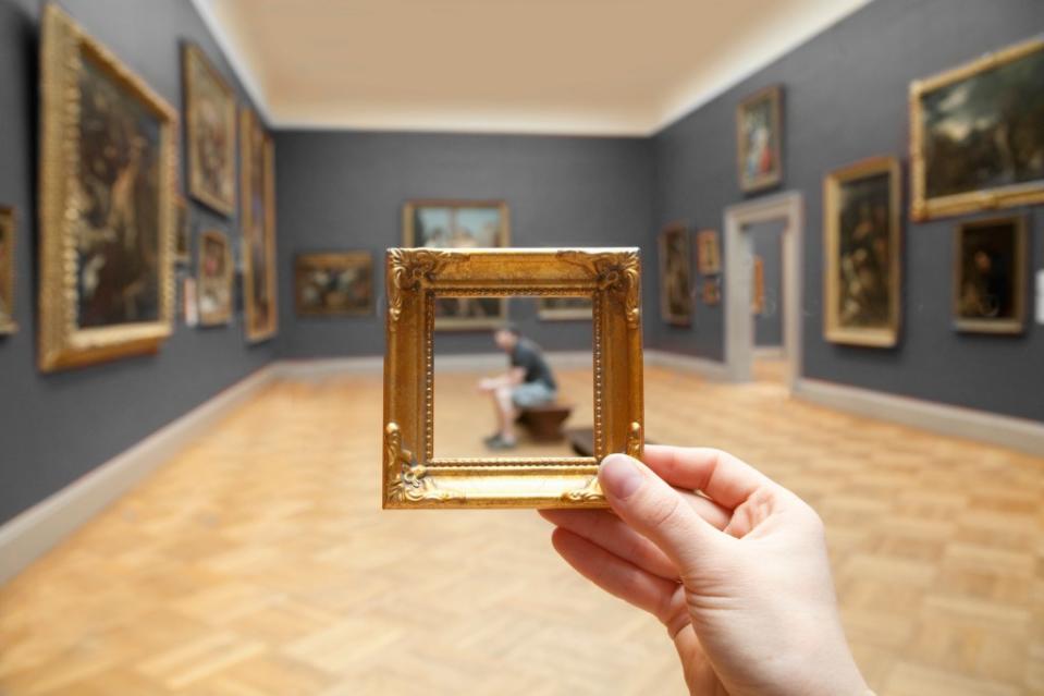 Young man sitting observing a painting framed by golden frame via Getty Images/Grant Faint