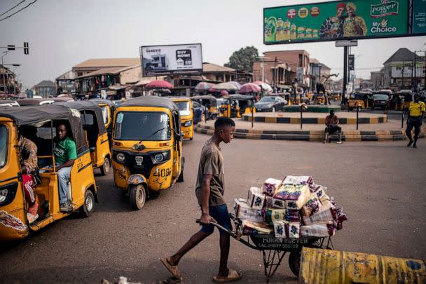 PHOTO: Tuk-tuks, or tricycles, carry customers in a local market as a vendor pushes a cart of goods in Anambra state, southeastern Nigeria, on Feb. 24, 2023. (Mosa'ab Elshamy/AP)