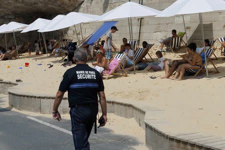 A French municipal policeman patrols along the banks of the Seine during the "Paris plage" event in Paris, France, August 12, 2015. REUTERS/Pascal Rossignol