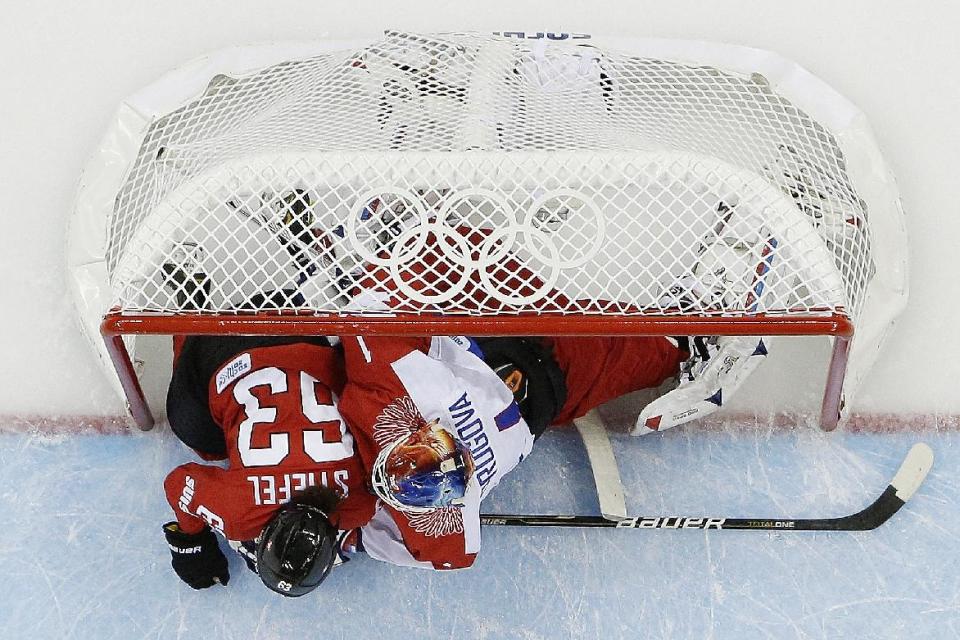 Anja Stiefel of Switzerland slides into the net with Goalkeeper Anna Prugova of Russia during the 2014 Winter Olympics women's ice hockey quarterfinal game at Shayba Arena, Saturday, Feb. 15, 2014, in Sochi, Russia. Switzerland defeated Russia 2-0. (AP Photo/Matt Slocum)