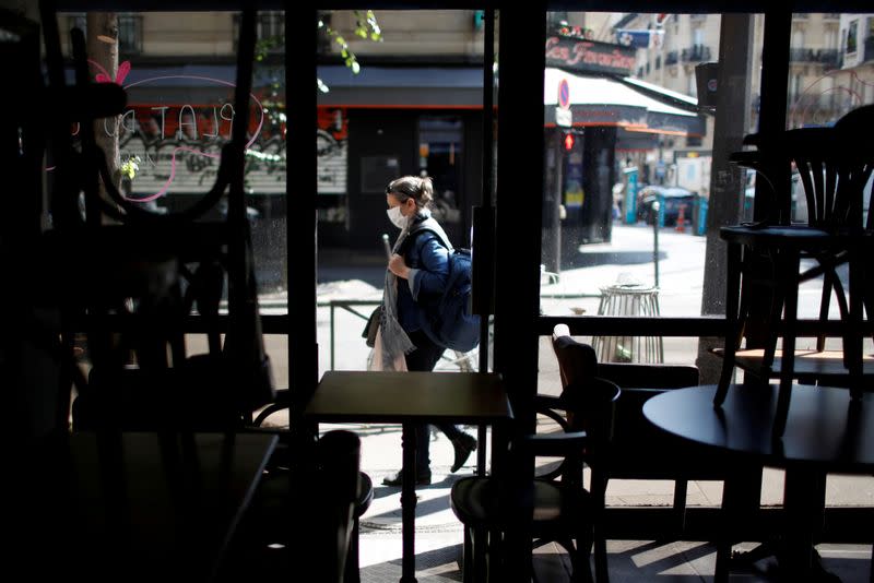 FILE PHOTO: A woman wearing a protective face mask walks past a closed restaurant in Paris