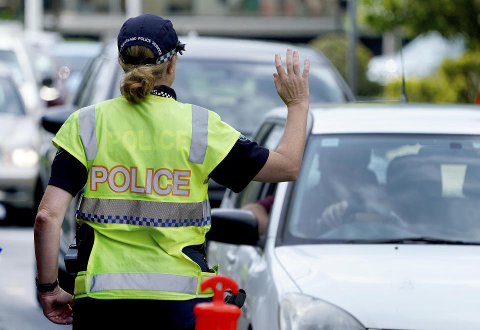 A police officer stops a driver at a checkpoint at Coolangatta on the Queensland/New South Wales border on Thursday. Source: AAP